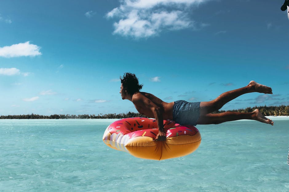 Man jumping into turquoise water with a donut float in French Polynesia