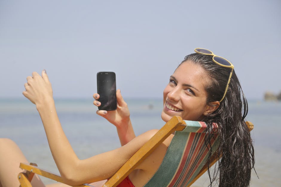 Smiling woman enjoying her vacation at Mgarr, Malta beach with a smartphone in hand