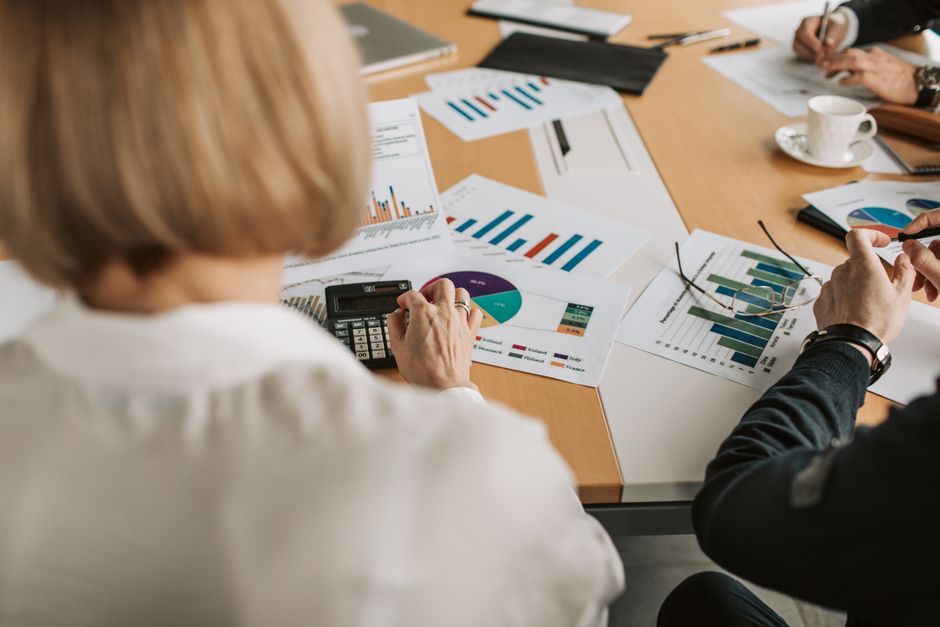 Profesionalci razmatraju financijske grafove i koriste kalkulatore u uredu